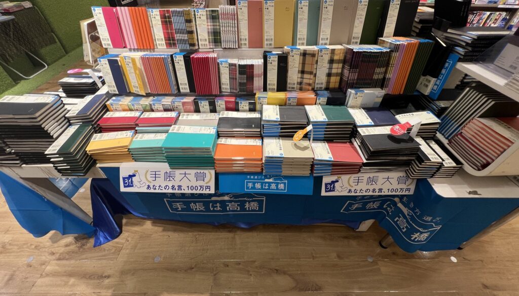書店の手帳売り場。高橋書店の2027年版が「手帳は高橋」のテーブルクロスの上に、用途別の帯を付けて並んでいる（2026年9月13日撮影）